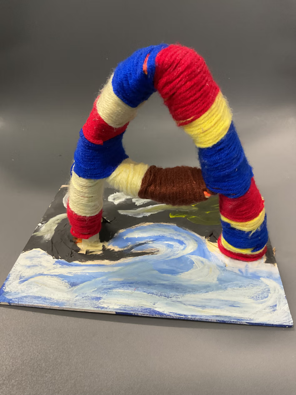 Student-made yarn-wrapped sculpture displayed on a painted base.